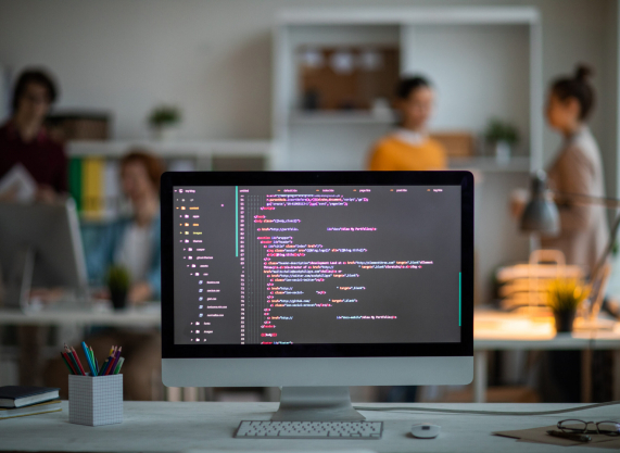 Workplace of it-developer or programmer with computer screen with coded data on background of office workers
